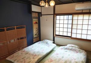 Un dormitorio con dos camas y dos ventanas. en Kyoto Villa Fuka, en Kioto