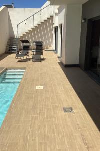 a patio with chairs and a pool on a building at HouseSleeps6-Pool-Beach-Garden-Solarium-PetOK in Playas de Orihuela