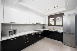 a kitchen with black cabinets and a stainless steel refrigerator at Villa Metis in Lachania