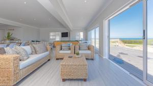 a living room with couches and a balcony with the ocean at Pondok Straat - Agulhas in Agulhas