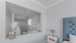 a white bathroom with a tub and a mirror at Pondok Straat - Agulhas in Agulhas +28 photos