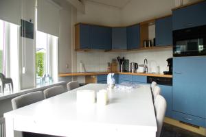 a kitchen with blue cabinets and a white table at De Golfakker in Hollum