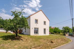 a white house on a hill with a tree at Maison Moderne et confortable pour 7 personnes in La Grande-Paroisse
