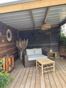 a patio with a couch and a table on a deck at La Cabane Mini Enchantée ! in Thenay