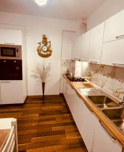 a kitchen with white cabinets and a clock on the wall at Laurent's Durres apartment in Durrës