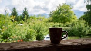 a coffee cup sitting on top of a wooden rail at AMA Bliss Nature & Cozy Cabin in Avrig