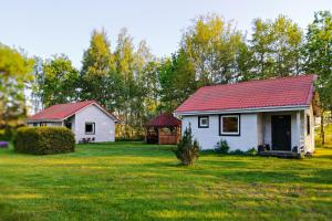 una piccola casa bianca con un tetto rosso in un cortile di Domki Irka nad morzem a Łeba
