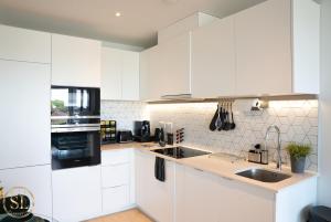 une cuisine blanche avec des armoires blanches et un évier dans l'établissement Luxury 2 Bedroom 2 Bathroom Apartment In Wimbledon, à New Malden