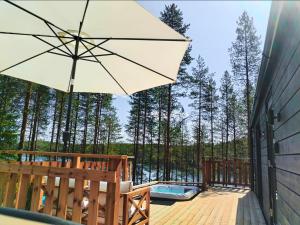 a patio with an umbrella and a tub on a deck at Hossaville Luxe Lake Cabin in Hossa