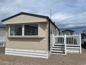 a small house with a porch and a white fence at J4 Lossiemouth Bay Caravan Park in Lossiemouth
