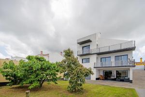 una casa blanca con un árbol delante en Casa da Orquidea, en Ribeira Grande