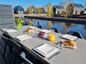 einen Tisch mit Teller Essen auf dem Tisch neben einem Fluss in der Unterkunft Luxurious detached water villa with jetty in Balk