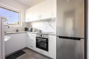 a kitchen with white cabinets and a stainless steel refrigerator at Varkizaki by the sea in Varkiza