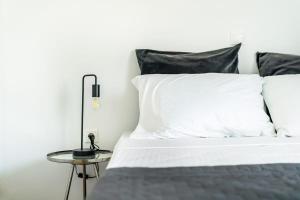a bed with white sheets and a lamp on a table at Varkizaki by the sea in Varkiza