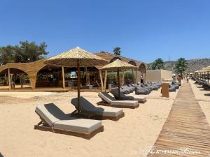 a row of lounge chairs and umbrellas on a beach at Varkizaki by the sea in Varkiza
