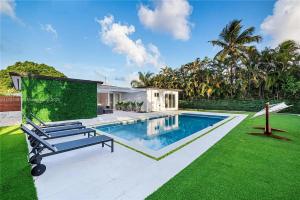 a house with a swimming pool and green grass at Miami Shores Modernist Villa in Miami Shores