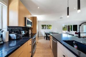 a kitchen with black counter tops and a dining room at Miami Shores Modernist Villa in Miami Shores