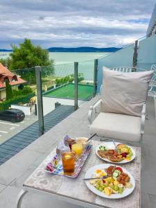 a table with two plates of food on a balcony at Lelle Marine Resort Voila Apartman in Balatonlelle