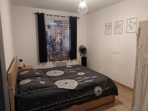 a bedroom with a bed with a black comforter at L'Escale Pernoise, 2-6 personnes in Pernes-les-Fontaines