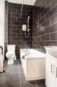 a bathroom with a tub and a toilet and a sink at South Beach Hotel in Troon