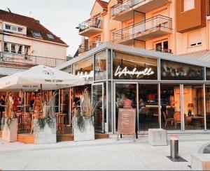 a restaurant with tables and chairs in front of a building at Le Studio Chic in Le Portel