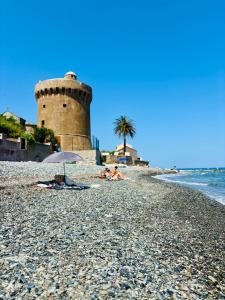 eine Gruppe von Menschen, die am Strand mit einem Leuchtturm liegen in der Unterkunft Appartement face à la mer in Santa-Maria-di-Lota