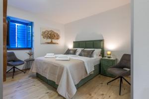 a bedroom with a large bed and two chairs at City Premium Heritage in Zadar