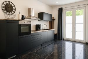 une cuisine avec des armoires noires et une horloge murale dans l'établissement Werre Apartments mit Smart-TV - stilvol, zentral & wohnlich, à Löhne