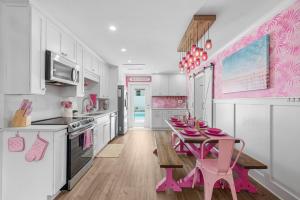 a pink kitchen with a table and pink stools at Pink Prerogative Beach Bungalow with Private Pool in Panama City Beach