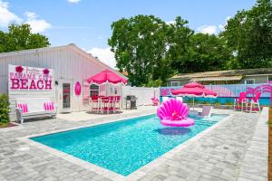 a swimming pool with pink chairs and pink umbrellas at Pink Prerogative Beach Bungalow with Private Pool in Panama City Beach