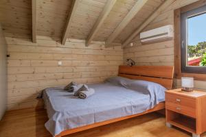 a bed in a wooden room with a window at Bright and cozy cottage near the sea in Káto Alepokhórion