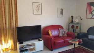 a living room with a red chair and a flat screen tv at AVIGNON hyper centre calme in Avignon