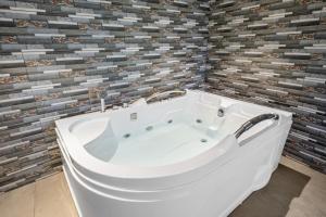 a bath tub in a bathroom with a tile wall at Leafy Lush Resort and Spa in Rāmnagar