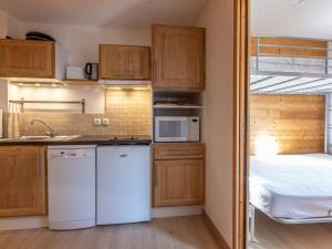 a kitchen with white appliances and a bed in a room at Studio cabine 5 personnes avec balcon - La Plagne - FR-1-353-85 in Les Coches