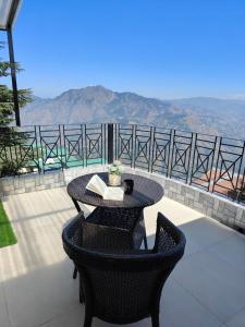 马舍布拉Hostie Heaven View - 3BHK Duplex with Terrace, Mashobra的一张桌子和几把椅子，可以欣赏到山景