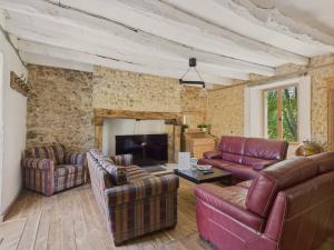 a living room with leather furniture and a stone wall at Au coeur de la Dordogne, maison pour 6, piscine in La Pinsonnie