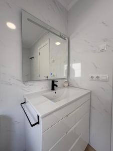 a white bathroom with a sink and a mirror at Apartamentos Cervera in Teulada +7 photos