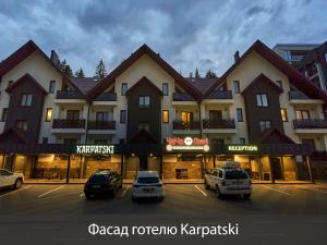a large building with cars parked in a parking lot at Karpatski Hotel & Spa in Bukovel