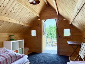 a bedroom in a wooden cabin with a bed and a door at Apart-Hotel Kastanienhof in Dannenfels