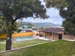 a house with a swimming pool and a tree at Pousada Sinai in Viçosa
