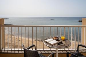a table with a plate of food on a balcony overlooking the beach at Checkin Diamar in Arrecife