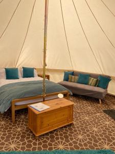 a bedroom with a bed and a couch in a tent at Fords Farm Glamping & Farm House in Oswestry
