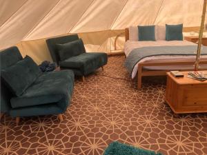 a room with a tent with a couch and a chair at Fords Farm Glamping & Farm House in Oswestry