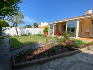 a house with a yard with a garden with flowers at Frangipanier, Maison quartier calme, 1,5km de la plage, 6 pers in Les Sables-d'Olonne