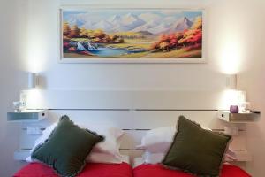 a painting hanging above a bed with pillows at La Riva del Sonno in Rivisondoli