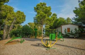 un parque con 2 columpios y un parque infantil en Camping 3 étoiles - Piscine - eehdai, en Sigean