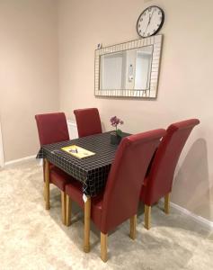 ein Esstisch mit roten Stühlen und einer Uhr an der Wand in der Unterkunft Private 1st Floor Apartment - Perfect for Port of Dover, Eurotunnel and Short Stays in Dover