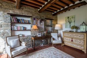 a living room with two chairs and a desk and a stone wall at Villa Valerie in Cortona