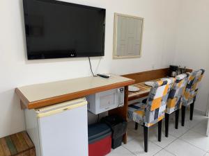 a room with a desk with a television and chairs at Riviera- Hotel Suite Família in Riviera de São Lourenço