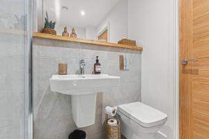 a bathroom with a white sink and a toilet at Luxury 2-Bed with Balcony & Secure Parking in Leeds +18 photos